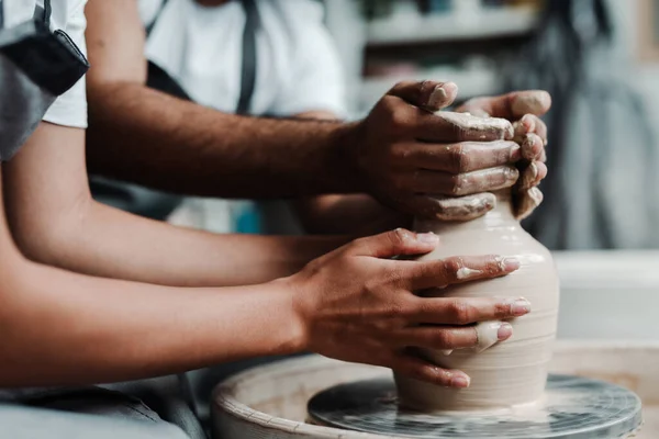 Photo proche et latérale. Les mains des hommes et des femmes font un vase d'argile. Date dans l'atelier — Photo