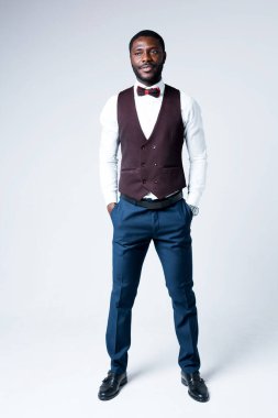 Tam boy fotoğraf. Yakışıklı Afro-Amerikan iş adamı elleri ceplerinde kameraya bakıyor.