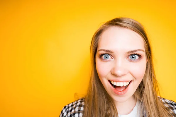 Retrato de uma menina bonita feliz em uma camisa xadrez olhando para a câmera e abrindo a boca — Fotografia de Stock