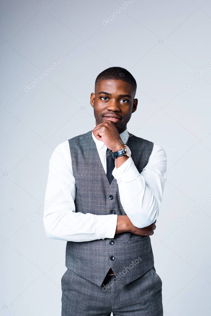 Handsome african american businessman leans on hand and rubs chin while looking at camera