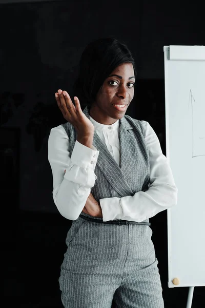 Αφροαμερικανή επιχειρηματίας με επίσημο κοστούμι στέκεται δίπλα στο λευκό πίνακα και δίνει μια διάλεξη — Φωτογραφία Αρχείου