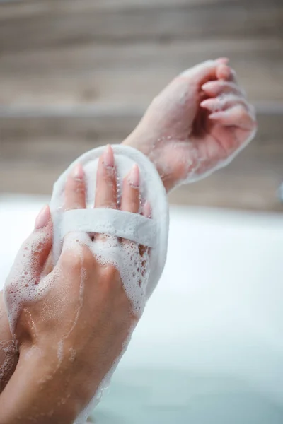 Las manos de las niñas con un paño están frotando el cuerpo con gel de ducha mientras están sentadas en el baño. Cuidado personal — Foto de Stock