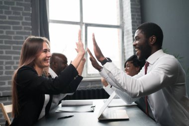 Yandan bir fotoğraf. Afrika kökenli Amerikalı iş adamları karşı masada oturan ve gülümseyen kızlara beş dolar veriyor.