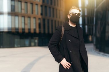 Siyah ceketli yakışıklı bir erkek turist ve koruyucu bir tıbbi maske şehirde dolaşıyor. Salgın sırasında turizm