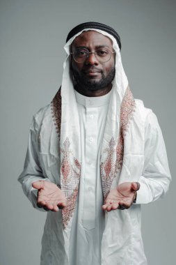 Uzun beyaz gömlekli genç bir Arap dua etmek için ellerini açar.