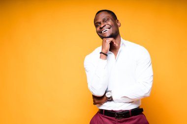 Koluna yaslanıp kameraya bakarken gülümseyen mutlu Afro-Amerikalı adam.