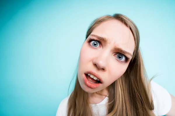 Une jeune fille mignonne dans un T-shirt blanc regarde indigné et surpris par la caméra avec sa bouche ouverte — Photo