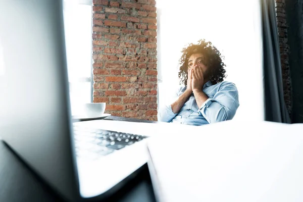 Afričtí američtí podnikatelé sedí u stolu a unaveně pracují na laptopu, dotýkají se dlaněmi obličeje. — Stock fotografie