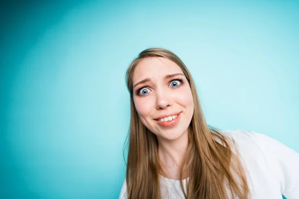 Roztomilé mladé dívky se usmívá překvapeně při pohledu na kameru naklánějící hlavu a stojí na modrém pozadí — Stock fotografie