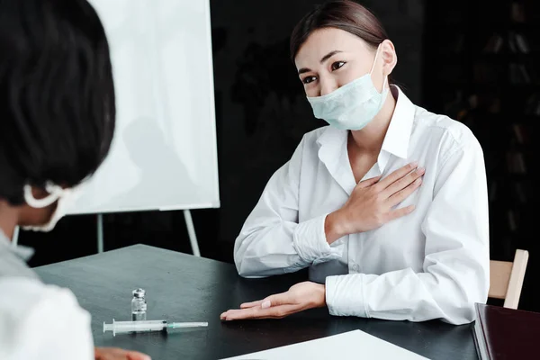 Умоляя азиатку-врача в медицинской маске подписать согласие на вакцинацию пациентки — стоковое фото