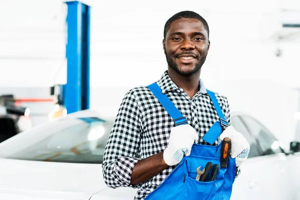 Africký americký mechanik v modrém dickey s nástroji uvnitř připraven opravit auta. — Stock fotografie