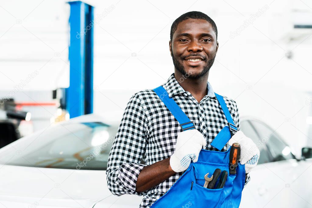 African american mechanic in blue dickey with instruments inside ready to repair cars.