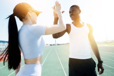 Beyaz tişörtlü siyah bir adam ve mavi elbiseli beyaz bir kadın yarıştan önce birbirlerini selamlıyorlar.