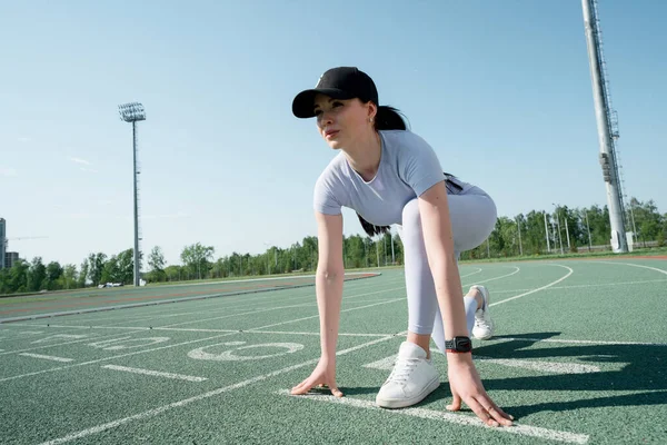 Un atleta asiático con un traje gris con una cara seria se para al principio y está listo para comenzar la carrera en el estadio Imagen De Stock