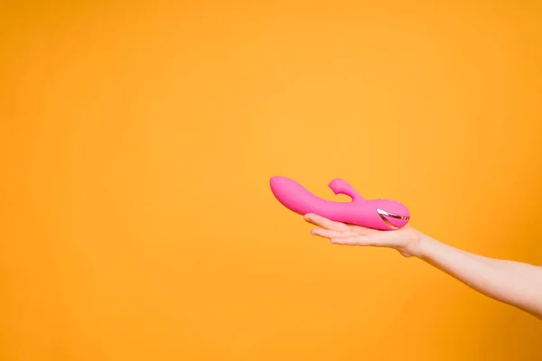 Sex gadgets and masturbation devices. Pink dildo in womans hand on orange background. sex toys — стоковое фото