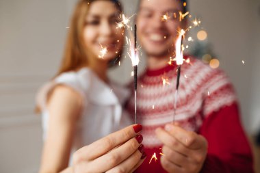 Genç evli çift ellerinde maytap tutuyor. Noel ağacının yanında dur, Noel 'de