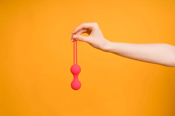 O mână feminină cu bile vaginale Kegel sau o jucărie sexuală pentru adulți pentru a obține un orgasm feminin pe un fundal galben — Fotografie, imagine de stoc