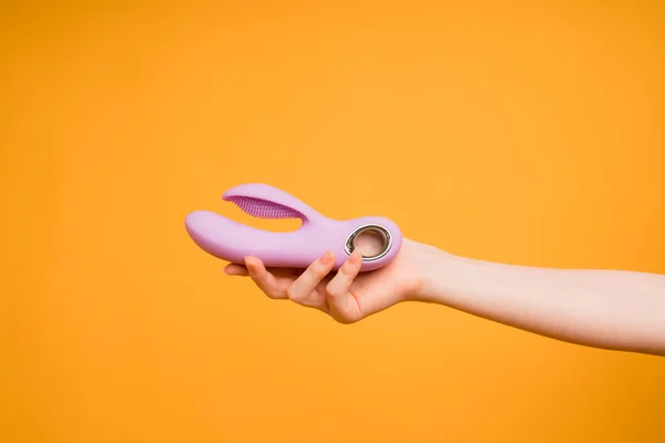 Gadget-uri sexuale și dispozitive de masturbare. Dildo roz la femei mână pe fundal portocaliu. jucarii sexuale — Fotografie, imagine de stoc