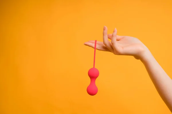 O mână feminină cu bile vaginale Kegel sau o jucărie sexuală pentru adulți pentru a obține un orgasm feminin pe un fundal galben — Fotografie, imagine de stoc
