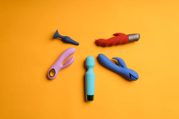 Обилие разноцветных дилдо на жёлтом фоне. Клиторальный массаж, секс-игрушки для поддержания здоровья женщин