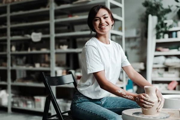 Mooi gelukkig aziatisch meisje het maken van een klei vaas in een workshop glimlachen en kijken naar de camera — Stockfoto