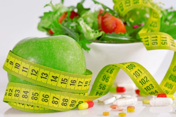 Conceito de dieta - maçãs verdes, alface, pílulas e fita métrica — Fotografia de Stock