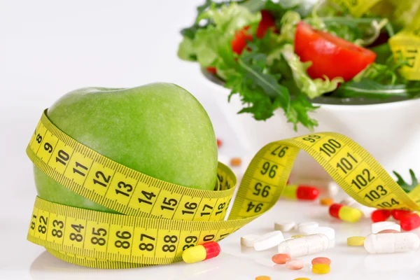 Ernährungskonzept - grüner Apfel, Tablette, Maßband und Salat — Stockfoto