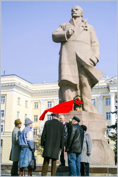 Seniors wiht reg flag speaking to each other under Lenin monumen — Stock Photo, Image