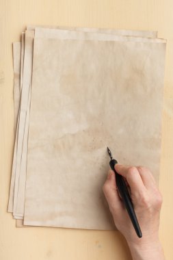 Eski kağıt üzerinde elinde mürekkep kalem
