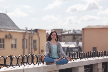 Lotus pozisyonu parapetin üzerinde genç kadın