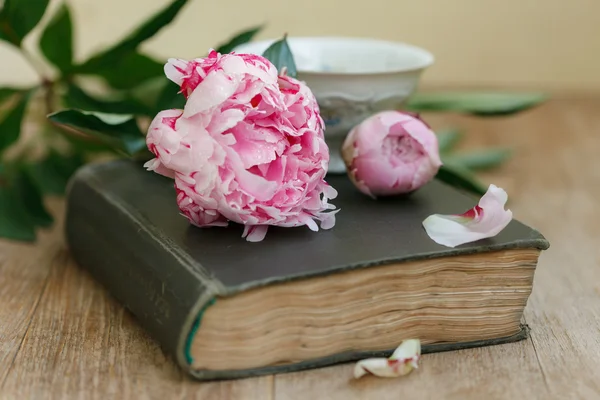 Book, flowers and cup on an old wooden table