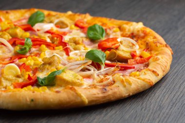 Eritilmiş mozarella peynirli İtalyan pizzası, zeytin ve sosis taze sebze ve fesleğen yapraklarıyla süslenmiş.