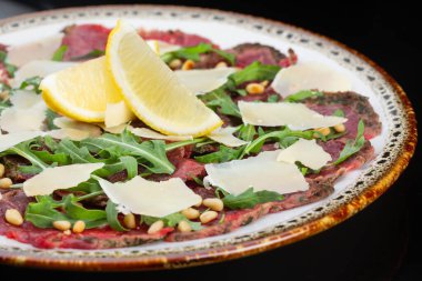 Yumuşak et carpaccio ve ince dilimler peynir, fındık ve bir dilim limon.