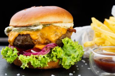 Ketçaplı domuz burger ve patates kızartması. Siyah arkaplanda tahta tahta