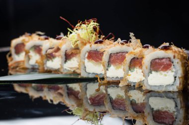Krem peynirli uramaki suşi dürümü, kızarmış somon, ton balığı talaşı ya da kurutulmuş bonito, salatalık, nori. Çubuklar Japon restoranında taze katsuobushi rulosu tutuyor.