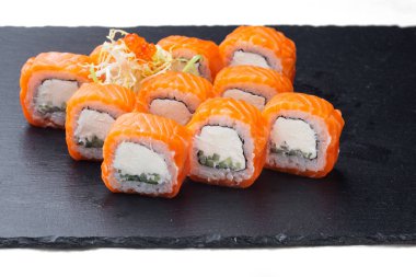 Traditional delicious fresh sushi roll set on a black background with reflection. Sushi roll with rice, cream chees, red fish, salmon. Sushi menu. Japanese kitchen, restaurant. Seafood, asian food