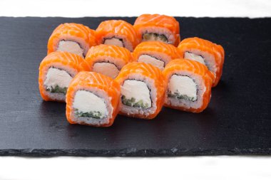 Traditional delicious fresh sushi roll set on a black background with reflection. Sushi roll with rice, cream chees, red fish, salmon. Sushi menu. Japanese kitchen, restaurant. Seafood, asian food