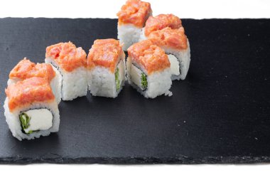 Traditional delicious fresh sushi roll on a black background with reflection. Sushi roll with rice, cream cheese, red fish, salmon. Sushi menu. Japanese cuisine, restaurant. Seafood, Asian cuisine. Baked sushi. Hot sushi