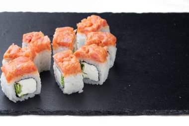 Traditional delicious fresh sushi roll on a black background with reflection. Sushi roll with rice, cream cheese, red fish, salmon. Sushi menu. Japanese cuisine, restaurant. Seafood, Asian cuisine