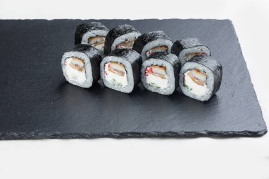 Somon, avokado ve peynirli suşi, beyaz tabakta siyah taştan bir tabakta. Suşi menüsü. Japon yemeği..