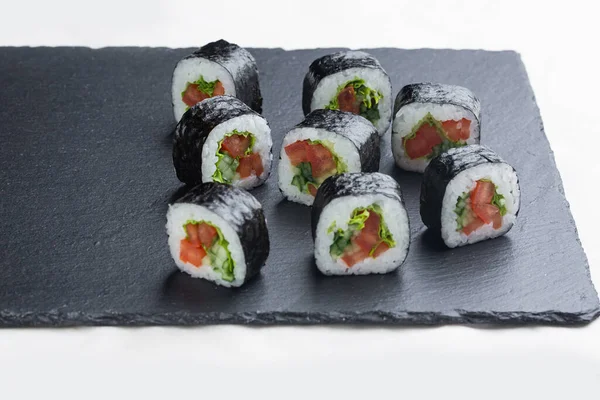 寿司卷与鲑鱼 鳄梨和奶酪在一个黑色的石板上的白盘 寿司菜单 日本菜 — 图库照片