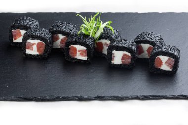 Somon, avokado ve peynirli suşi, beyaz tabakta siyah taştan bir tabakta. Suşi menüsü. Japon yemeği.