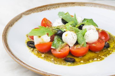 Taze kiraz domatesli Caprese salatası, mini mozzarella, pesto, fesleğen, beyaz tabakta zeytinyağı ve balzamik sos ve beyaz arka plan diyet konsepti. İtalyan sağlıklı yemekleri.