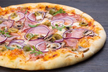 Taze domatesli, zeytinli, soğanlı, sosisli, jambonlu ve fesleğenli lezzetli İtalyan pizzası.