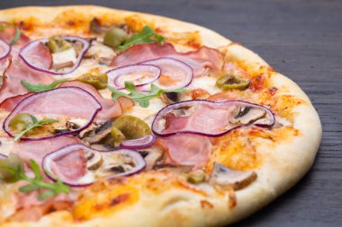 Taze domatesli, zeytinli, soğanlı, sosisli, jambonlu ve fesleğenli lezzetli İtalyan pizzası.