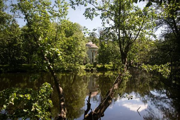 Göletin ortasındaki bir adadaki parkta sütunları olan mimari bir kasa.   