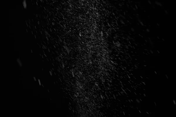 Snow from spray can stream out then fall down slowly in center on black background for overlay effect