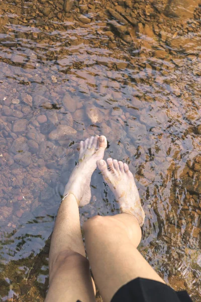 黒いスカートの女性は水に足を入れ反射して川の下に石を持っている — ストック写真