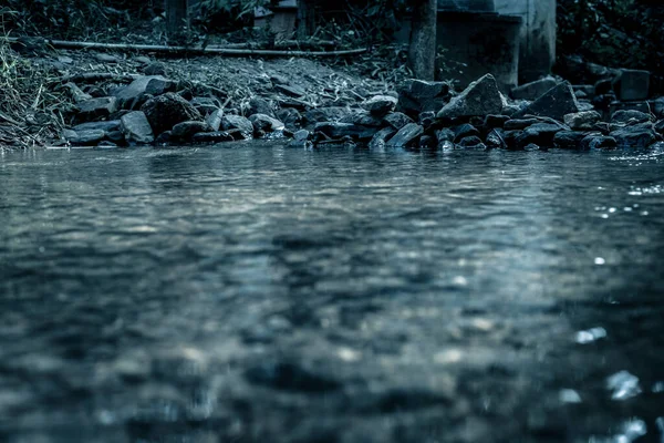 手前に反射のある川の近くの石で作られた堰 劇的な恐怖のトーンで — ストック写真