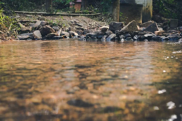 前景に反射のある川の近くの石で作られた堰 — ストック写真